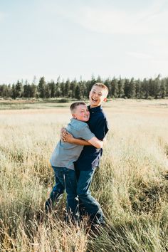 two boys hugging each other in a field