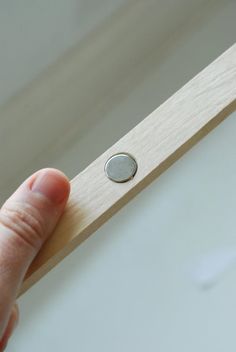 a hand holding a wooden object with a button on it