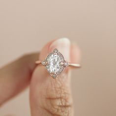 a woman's hand holding an engagement ring with a diamond center stone in the middle