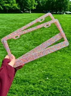 a person holding up a plastic object in the grass