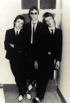 three men in suits and ties standing next to each other near a door with their arms around one another