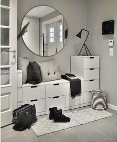 black and white photograph of a bedroom with shoes on the floor in front of a round mirror