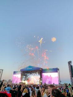 a large group of people at an outdoor concert watching fireworks go off in the sky