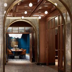 an archway leads into a dining room with blue walls and wood paneling on the ceiling