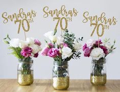 three mason jars with flowers in them on a table