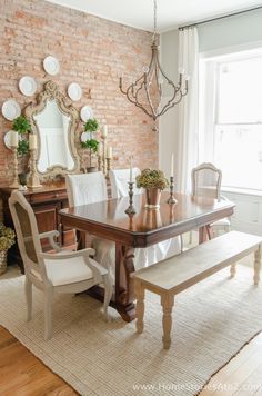 a dining room table with two chairs and a bench in front of a brick wall