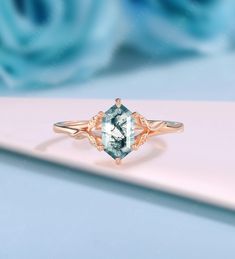 a blue diamond ring sitting on top of a white table next to flowers and roses