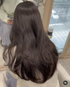 the back of a woman's head with long dark hair in front of a mirror