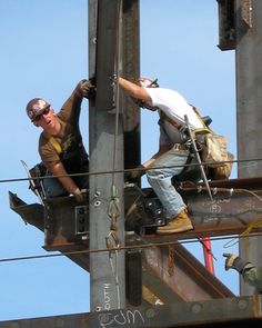 two men working on the side of a tall building