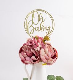 a white vase filled with pink flowers on top of a table