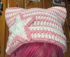 a woman with pink hair wearing a crocheted hat