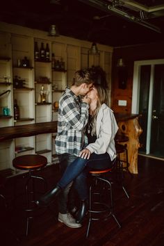 a man and woman sitting on top of stools in a kitchen next to each other