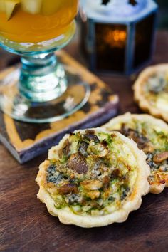 small appetizers are sitting on a table next to a glass of beer and an apple