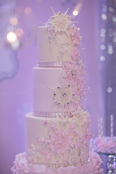 a three tiered wedding cake with pink flowers and pearls