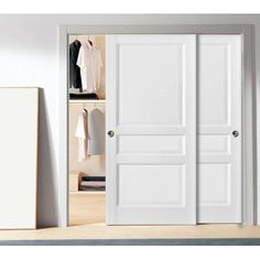 an open closet door with clothes hanging on the wall and a white cabinet below it