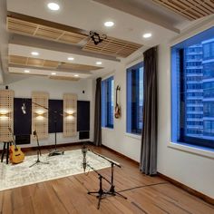 an empty room with guitars and microphones on the floor in front of large windows