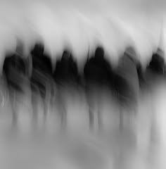 black and white photograph of people standing in front of each other with blurry background