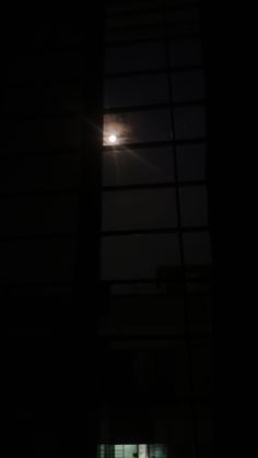 the moon is shining brightly in the dark night sky over a window with blinds on it