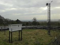 an empty box in the middle of a grassy field with power lines and hills in the background