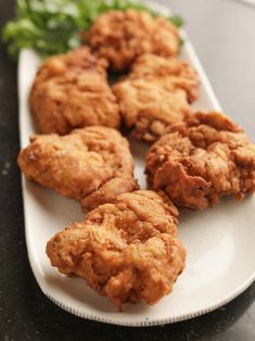 some fried food on a white plate with lettuce in the backgroung