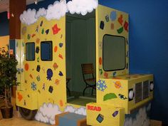 a child's play area in the shape of a yellow truck with clouds and stars painted on it