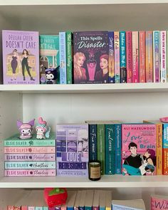 several books are stacked on top of each other in a white bookcase with pink and blue covers