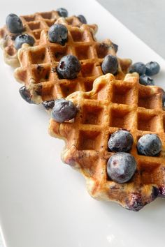 two waffles with blueberries on them are sitting on a white platter