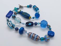 Handmade LAMPWORK MURANO fish necklace with various style glass blue beads, Unique costume jewelry, Murano blue jewellery, Lampwork necklace Gorgeous handmade Murano blue glass necklace with various styled lampwork beads that are each individually handmade. The necklace has a mix of styled art glass that includes cylindrical, squares and round and even a fish that are also hand strung. A beautiful and unique piece of statement handmade jewellery that would be a talking point in any occasion.  Th Blue Jewellery, Lampwork Necklace, Fish Necklace, Unique Costumes, Blue Jewelry, Glass Necklace, Handmade Jewellery, Lampwork Beads, Vintage Jewellery