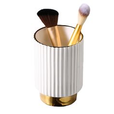 two brushes in a white cup with gold trimmings on the rim and inside