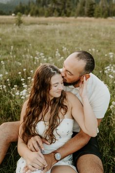 a man and woman sitting in the grass together