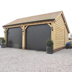 a large garage with two cars parked in front of it and a shed on the other side