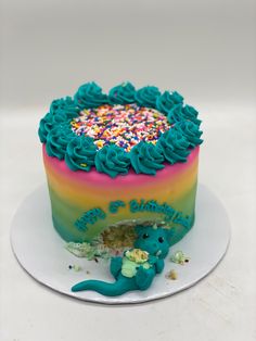 a birthday cake with blue frosting and sprinkles on the top is sitting on a plate