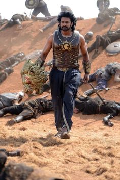 a man walking on top of a dry grass covered hillside next to dead animals and people