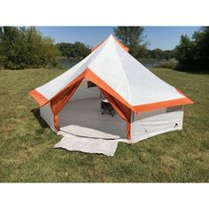 an orange and white tent sitting on top of a lush green field