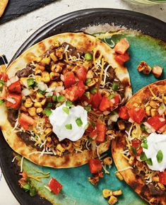 two tacos with toppings are on a plate next to some other food items