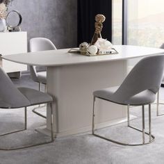 a white table with four grey chairs around it