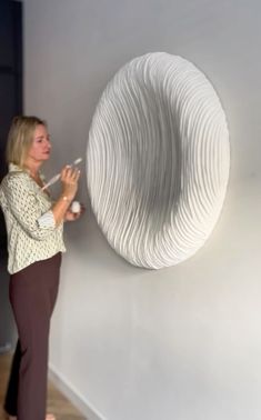 a woman standing in front of a white sculpture