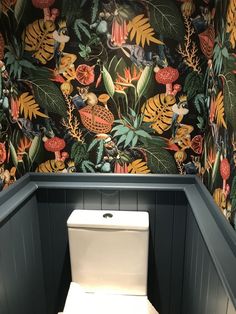 a toilet in a bathroom with floral wallpaper