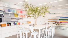 a white table and chairs in a room with shelves full of fabrics on the wall