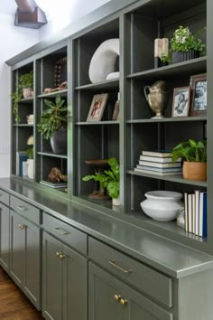 a green bookcase filled with lots of books next to a wall mounted planter