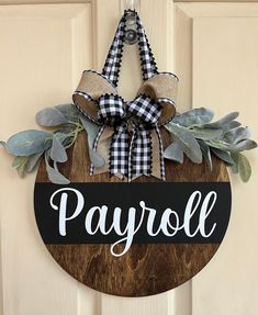 a wooden sign that says payroll hanging on a door with leaves and ribbon around it