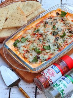 a casserole dish with cheese, spinach and other ingredients on a wooden board