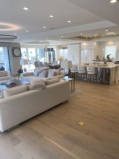 a living room filled with furniture next to a kitchen and dining room table in front of a large window