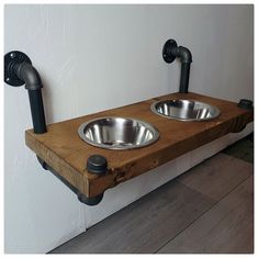 two stainless steel bowls are on a wooden shelf with black faucets and pipe handles