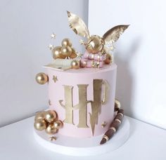 a pink and gold birthday cake with decorations on it's top, sitting on a table