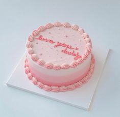 a pink and white cake with the words happy birthday on it sitting on top of a card