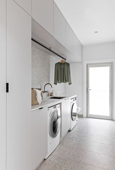 a washer and dryer in a white laundry room with an open door to the outside