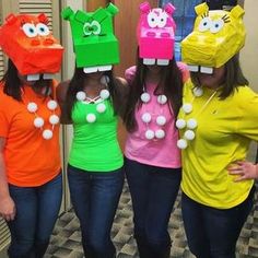 three girls wearing paper hats with faces painted on them, standing in front of a door