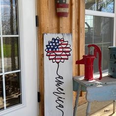 an american flag painted on a sign next to a door with a red fire hydrant