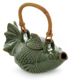 a green fish shaped teapot with wooden handle